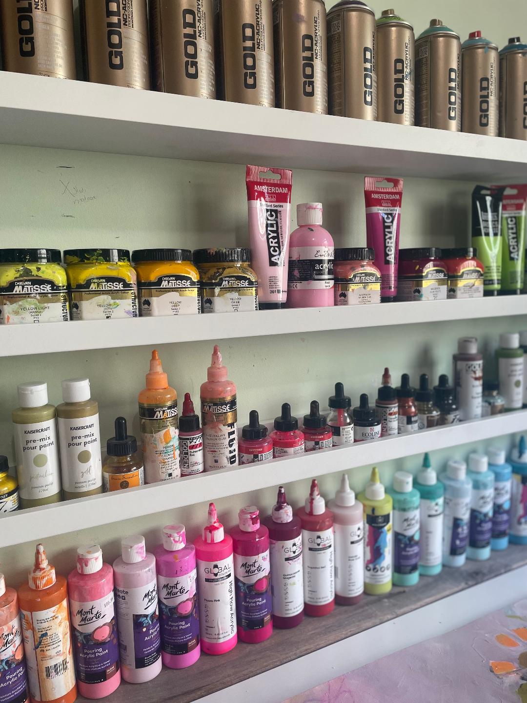 Narrow shelves displaying my paints all colour coded